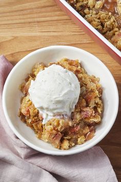 a white bowl filled with food on top of a wooden table next to a pink napkin