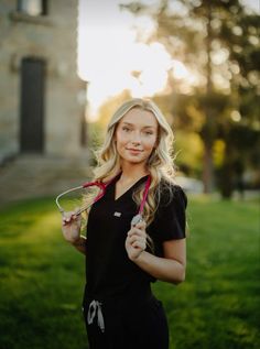 a woman holding a pair of scissors in front of her face while standing on the grass