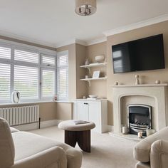 a living room filled with furniture and a flat screen tv mounted on the wall above a fire place