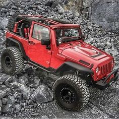 a red jeep is parked on some rocks