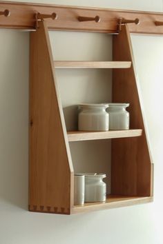 two wooden shelves with white containers on them and one shelf holding three jars in it