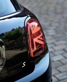 the back end of a black car on a cobblestone street