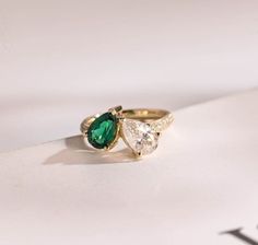 two pear shaped green and white diamonds on top of a gold ring with the word love written below it