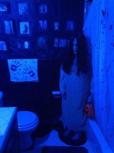 a woman standing in a bathroom with blue lights on the shower curtain and rugs