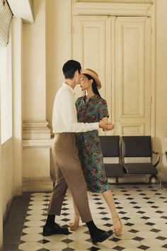 a man and woman are dancing in an old fashion room with black and white checkered flooring