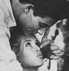 an old black and white photo of a man kissing a woman's head with her finger