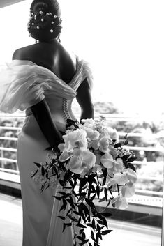 a black and white photo of a woman in a wedding dress holding a flower bouquet