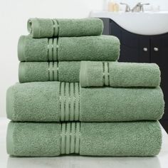 a stack of green towels sitting on top of a bathroom counter