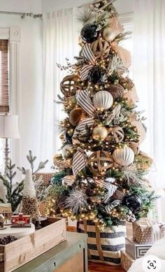 a decorated christmas tree in a living room with white walls and wooden flooring, gold ornaments