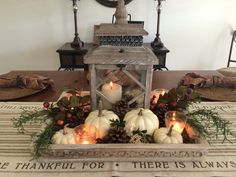 there is a lantern with candles in it on top of a dining room table decorated for thanksgiving