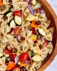 a wooden bowl filled with pasta and vegetables