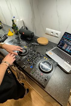 a person sitting in front of a laptop computer on top of a table with dj equipment