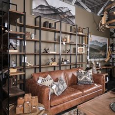 a brown leather couch sitting in front of a wooden shelf filled with pictures and other items