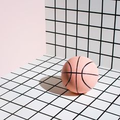 a pink ball sitting on top of a white tiled floor next to a black and white wall