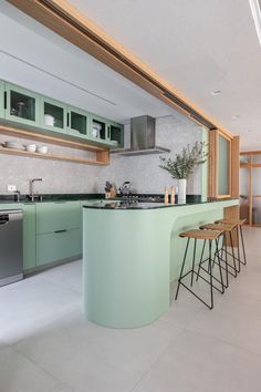 a modern kitchen with green cabinets and counter tops, two stools in front of the bar