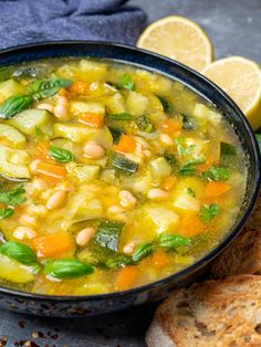 a bowl filled with soup next to sliced lemons and bread on top of a table