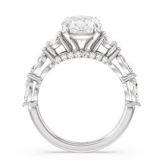 a white gold engagement ring with three stones on the band and an oval center stone surrounded by small baguetts