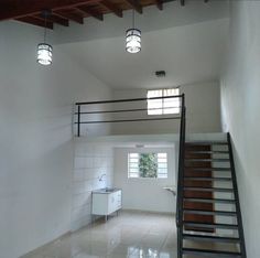 an empty room with white tile floors and wooden staircase leading up to the second floor