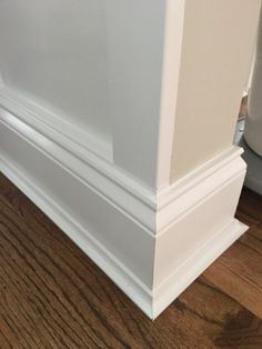 the corner of a room with wood flooring and white trim on it's walls