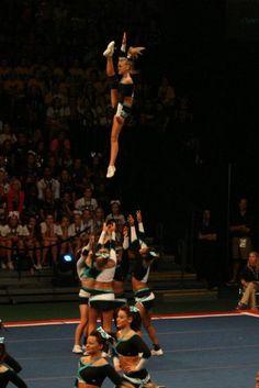 a group of cheerleaders performing stunts in front of an audience