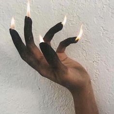 a person holding out their hand with three candles in it's palm, against a white wall