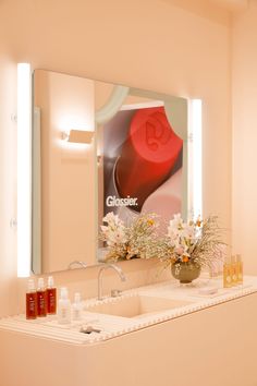 a bathroom with a sink, mirror and flowers