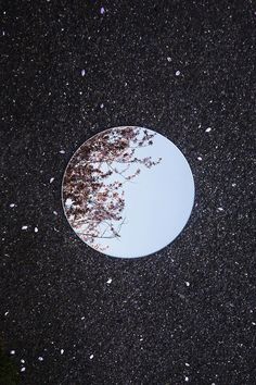 a round mirror sitting on top of a black floor covered in snow and small white bubbles