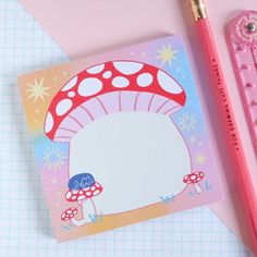 a pink pencil next to a piece of paper with a mushroom on it