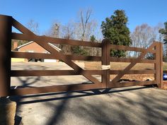 a wooden gate in the middle of a driveway