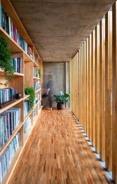 a person walking down a wooden floor next to bookshelves