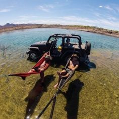 two canoes are in the water next to an old jeep that has been pulled over