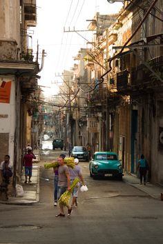 two people walking down the street with bananas on their heads and one person carrying bags