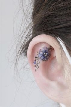 a close up of a person with a flower tattoo on their left behind the ear