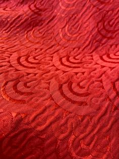 an orange and red bedspread with swirly designs on the bed coverlet