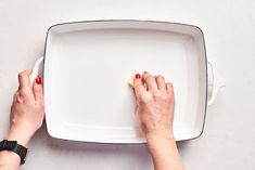 two hands on a white platter with red nail polish holding an empty square plate