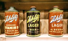 three cans of beer sitting on top of a wooden shelf