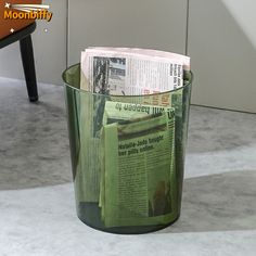 a trash can with newspapers in it sitting on the floor