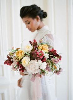 a woman holding a bouquet of flowers in her hands