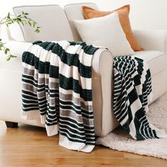 a white couch sitting next to a green and white blanket on top of a wooden floor