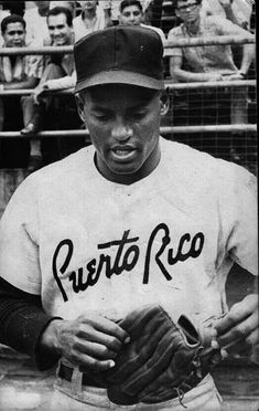 a black and white photo of a baseball player holding a glove in front of a crowd