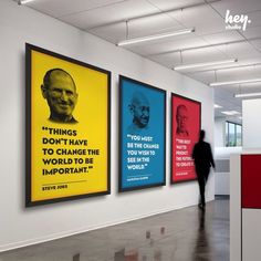 an office with three posters on the wall and a person walking past it in front of them