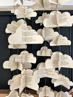 a bunch of paper clouds hanging from the side of a wall with words written on them