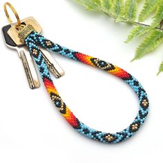 a keychain with two keys on it next to a fern leaf and other items