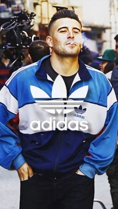 a man standing in front of a camera with his hands on his hips and the words adidas behind him