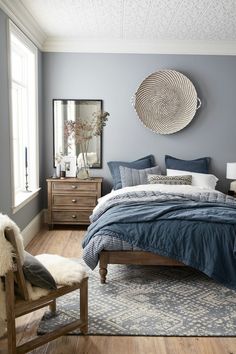 a bed room with a neatly made bed and a chair in front of a window