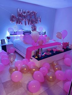 pink balloons and streamers are on the floor in front of a bed with a birthday sign