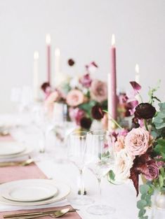 the table is set with white plates and pink napkins, silverware, and flowers