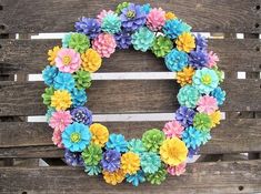 a wreath made out of paper flowers sitting on top of a wooden pallet