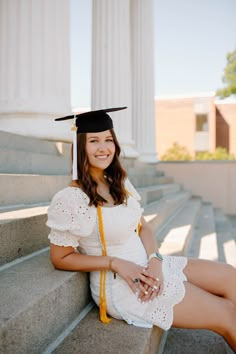 a woman in a graduation cap and gown sitting on steps