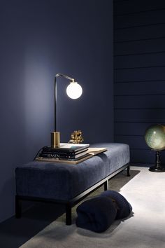 a room with a blue couch, lamp and books on the table in front of it